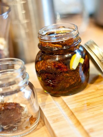 Rezept Foto von den eingelegten getrockneten Tomaten. Das Foto zeigt ein Einweckglas voller getrockneter Tomaten und eine Flasch Olivenöl.