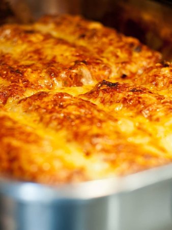 Rezept Foto von Enchilladas. Das Foto zeigt einen Blick in den Backofen. Die Enchilladas sind in der Edelstahlform fast fertig gebacken. Gold gelb färbt sich der Käse. Gleich ist es soweit.