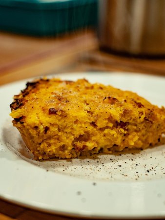 Rezept Foto der Kürbisquiche. Das Foto zeigt die noch dampfende Kürbisquiche. Angerichtet auf einem runden Teller, garniert mit frischem Pfeffer aus der Mühle.