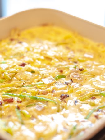 Rezept Foto des Lauchzwiebelkuchens. Das Foto zeigt die noch nicht gebackene Lauchzwiebelkuchen Masse in einer Kuchenspringform. Gleich kommt Sie in den Ofen.