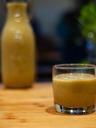 Rezept Foto vom Grünen Power Smoothie. Das Foto zeigt den fertigen, weichen Smoothie in einem Glas. Dahinter steht der übrige Smoothie in einem Weckglas.