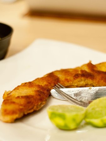 Eine Detailaufnahme vom Wiener Schnitzel mit Kartoffelsalat. Das Schnitzel ist goldbraun gebraten und raucht noch, da es gerade frisch aus der Pfanne gekommen ist.