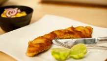 Eine Detailaufnahme vom Wiener Schnitzel mit Kartoffelsalat. Das Schnitzel ist goldbraun gebraten und raucht noch, da es gerade frisch aus der Pfanne gekommen ist.