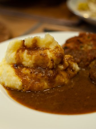 Rezept Foto vom Oberpfälzer Kartoffelstampf. Der Kartoffelbrei ist auf einem Teller serviert, mit einem Mungbohnenbratling und einer vegetarischen Bratensauce.