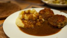 Rezept Foto vom Oberpfälzer Kartoffelstampf. Der Kartoffelbrei ist auf einem Teller serviert, mit einem Mungbohnenbratling und einer vegetarischen Bratensauce.