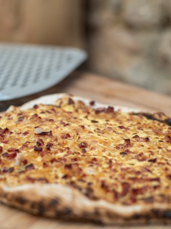 Rezept Foto vom Elsässer Flammkuchen fertig gebacken auf einem Schneidebrett serviert.