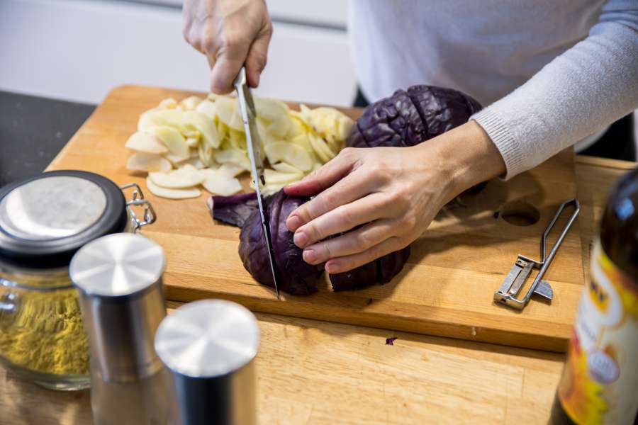 Rezept Foto Blaukraut. Der Rotkohl wird gerade von Katharina in Viertel gschnitten und der Strunk mit einem Küchenmesser entfernt.