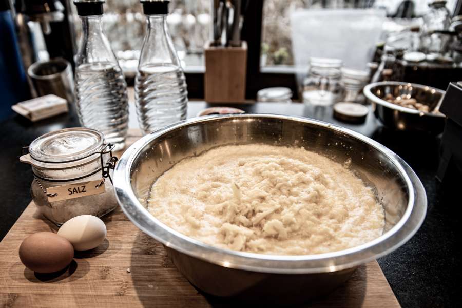 Der fertig geriebebe Kartoffelteig liegt in einer Schüssel mit den Zutaten bereit.