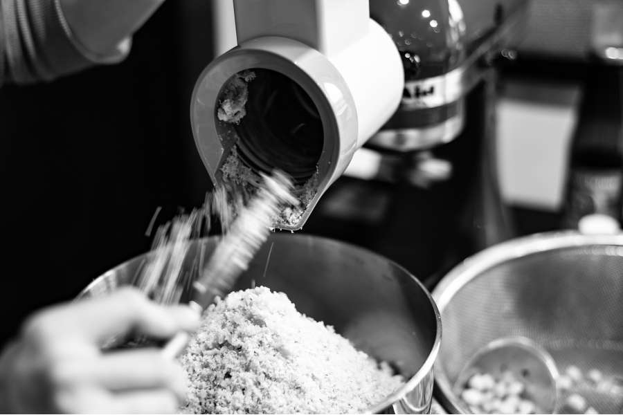 Rezept Foto der Falaffeln. Die Kichererbsen werden gerade durch die Kartoffelreibe gedreht und in einer Rührschüssel aufgefangen.