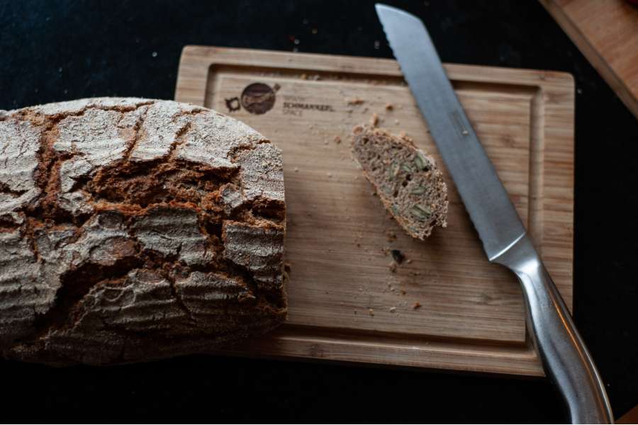 Rezept Foto Detailaufnahme Kürbis Creme Suppe das frische Holzofenbrot wird geschnitten und zur Suppe gereicht