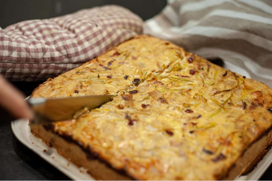 Rezept Foto Lauchzwiebelkuchen backen und genießen. Der Lauchzwiebelkuchen wurde aus der Form genommen und mit einem Messer in Häppchen geschnitten.