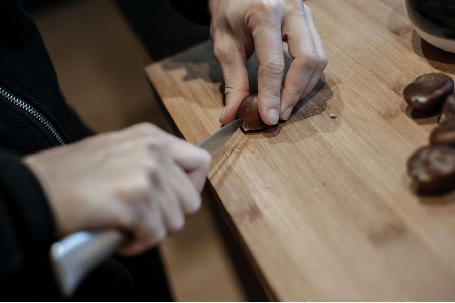 Rezept Foto Maronenrisotto. Katharina ritzt mit einem scharfen Messer kreuzweise die Maronen ein.