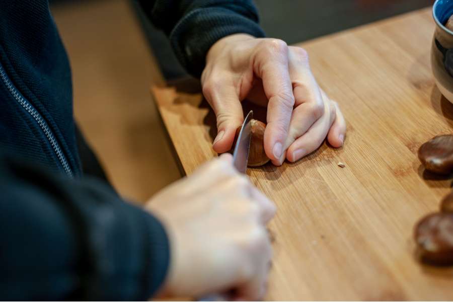 Rezept Foto Maronenrisotto. Detailaufnahme Katharina ritzt mit einem scharfen Messer kreuzweise die Maronen ein.