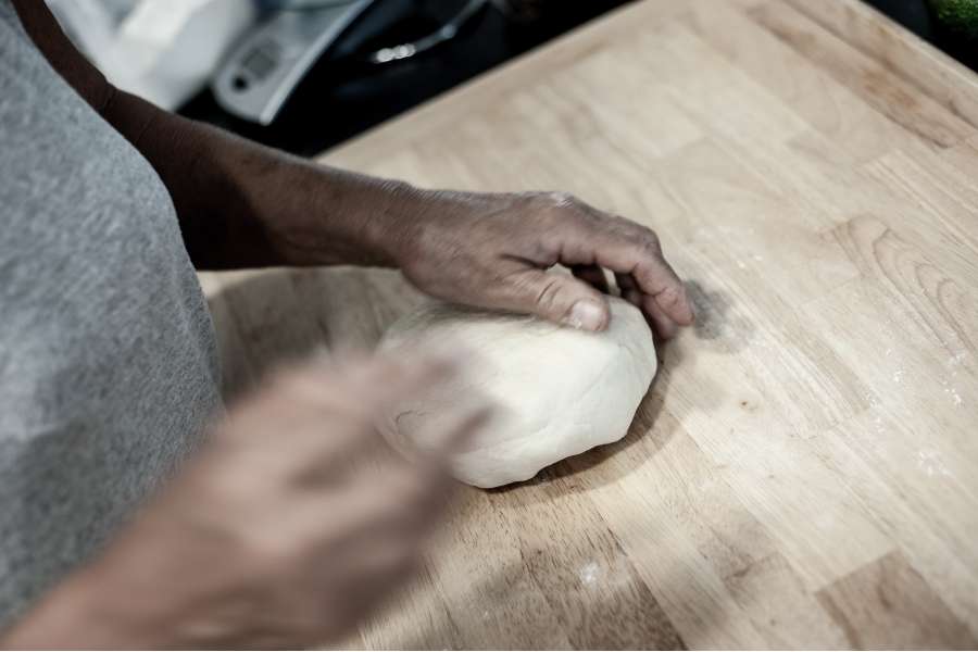 Rezept Foto Oberpfälzer Milchrahm Apfelstrudel. Nahaufnahme Mama Siglinde knetet den Teig nachdem rühren mit den Händen und wirft ihn immer wieder auf das Schneidebrett.