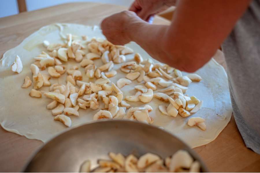 Rezept Foto Oberpfälzer Milchrahm Apfelstrudel. Der ausgerollte Studelteig füllt sich langsam nach und nach mit Apfelstückchen.