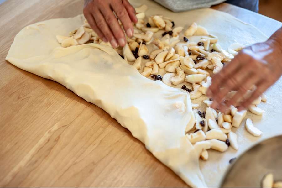 Rezept Foto Oberpfälzer Milchrahm Apfelstrudel. Mama Siglinde faltet den Teig an den Ecken ein.