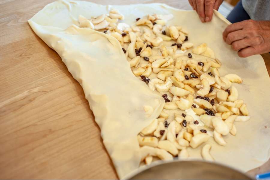 Rezept Foto Oberpfälzer Milchrahm Apfelstrudel. Mama Siglinde schlägt den Teig an den Ecken ein.