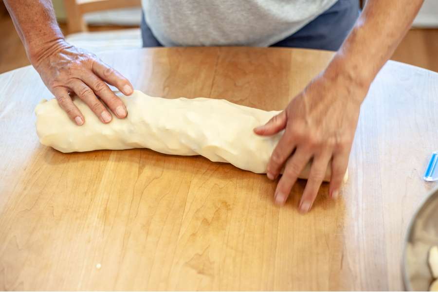 Rezept Foto Oberpfälzer Milchrahm Apfelstrudel. Mama Siglinde rollt den Teig in einem Schlauch zusammen.