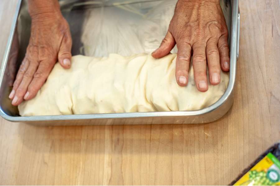 Rezept Foto Oberpfälzer Milchrahm Apfelstrudel. Mama Siglinde packt den Teig in den bepinselten Bräter.