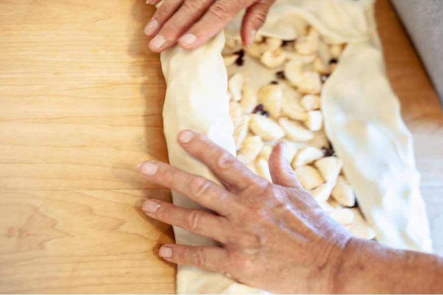 Rezept Foto Oberpfälzer Milchrahm Apfelstrudel. Mama Siglinde rollt den Teig wieder behutsam zusammen.