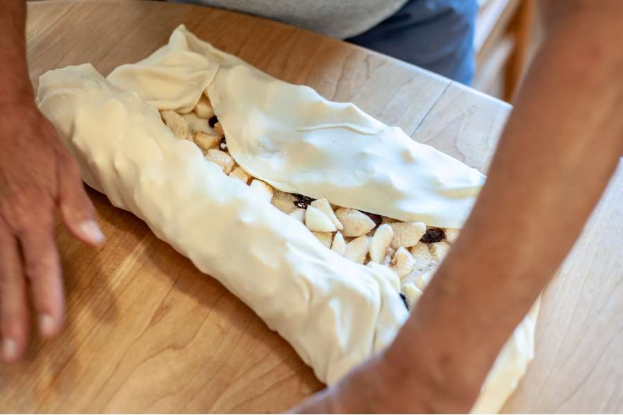 Rezept Foto Oberpfälzer Milchrahm Apfelstrudel. Seitenaufnahme: der Teig ist beinahe zusammengerollt.