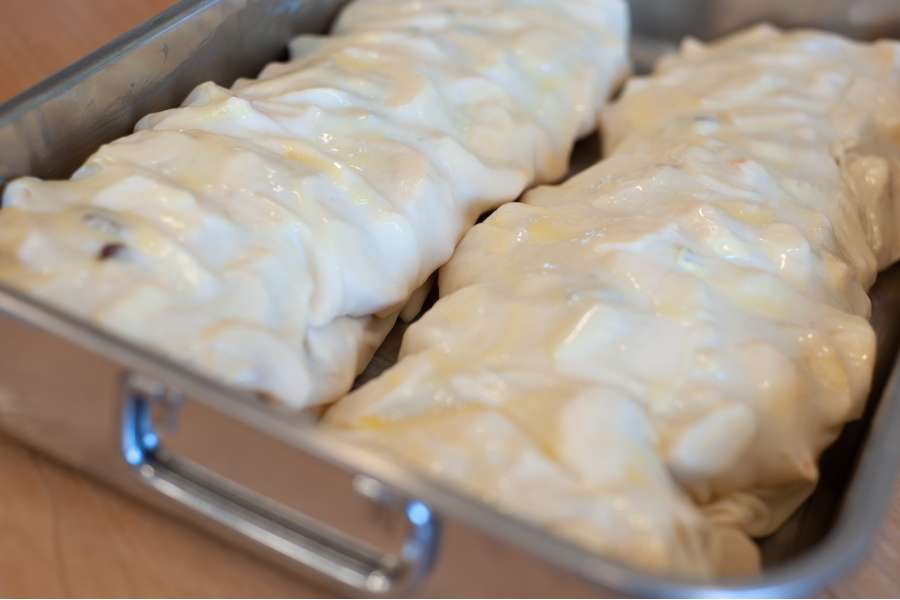 Rezept Foto Oberpfälzer Milchrahm Apfelstrudel. Beide Strudel liegen im Bräter nebeneinander und warten daruf in den Ofen geschoben zu werden.