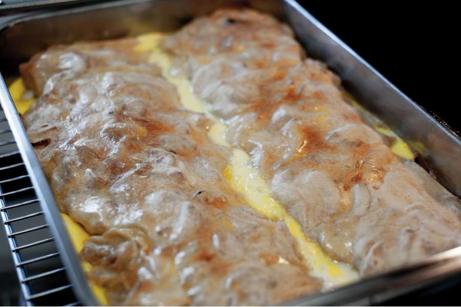 Rezept Foto Oberpfälzer Milchrahm Apfelstrudel. Der fertige Strudel dampft in der Form vor sich hin und wird gleich angeschnitten.