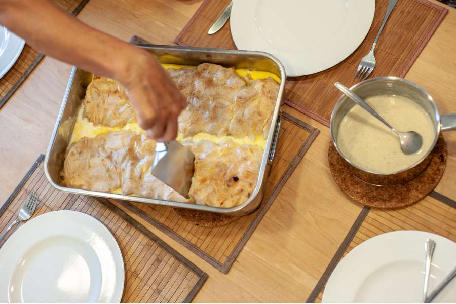 Rezept Foto Oberpfälzer Milchrahm Apfelstrudel. Katharina schneidet ein Stück Milchrahmstrudel heraus.