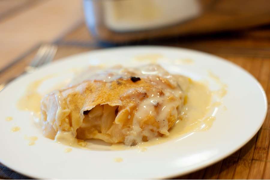 Rezept Foto Oberpfälzer Milchrahm Apfelstrudel. Seitenansicht: Oberpfälzer Milchrahmstrudel angerichtet auf einem china bone Teller mit Vanillesoße.