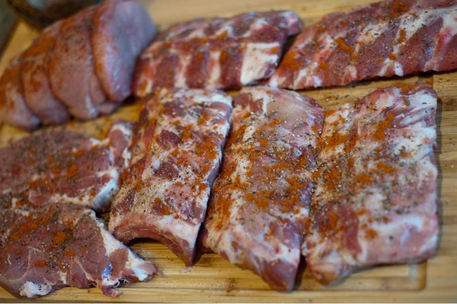 Rezept Foto Bayerischer Schweinebraten in der Kümmelbiersoße. Detailaufnahme von den Schweinerippchen ohne Knorpel mit viel Gewürzen wie Paprikapulver und Kümmel bestreut.