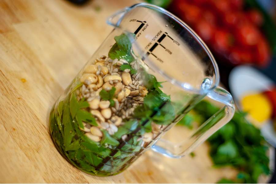Rezept Foto Kräuter und Garten Pesto. Messbecher mit Kräutern und Nüssen und Kernen darin.