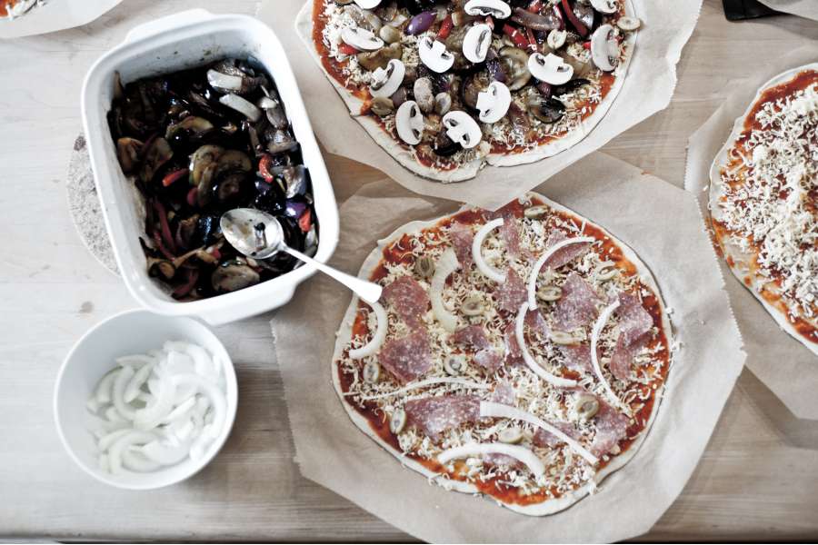 Rezept Foto Grillpizza und Ofenpizza Italien. Vogelperspektive über die belegten Pizzas und Zutaten.