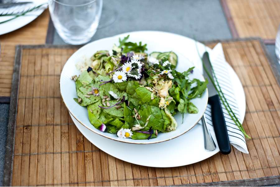 Rezept Foto Grillpizza und Ofenpizza Italien. Der Gartensalat wird auf einen runden Teller mit Goldrand garniert. Gänseblümchen aus unserer Wiese schmücken ihn zusätzlich.