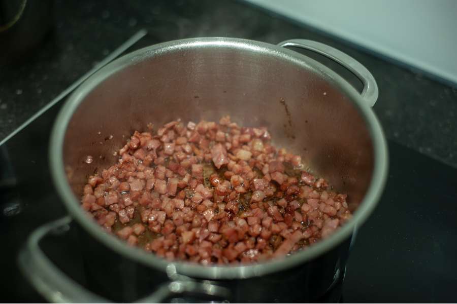 Rezept Foto Kürbis Quiche selber machen. Ein Blick in den Topf, in dem der Speck knusprig braun gebraten wird.
