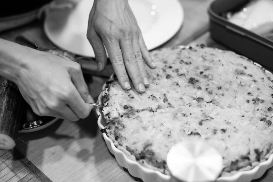 Rezept Foto Kürbis Quiche selber machen. Katharina hat die frische Quiche gerade eben angeschnitten und hebt vorsichtig das erste Stück heraus.