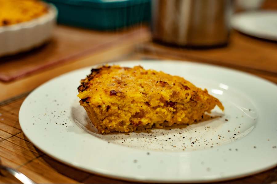 Rezept Foto Kürbis Quiche selber machen. Hokkaido Kürbis Quiche angerichtet auf einem weißen china bone Teller mit Salz und Pfeffer garniert.