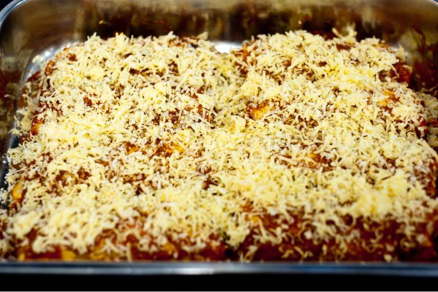 Rezept Foto Mexikansiche Enchillada. Die Enchilladas werden gerollt und nebeneinander in einen Bräter gelegt und mit der restlichen Tomatensauce übergossen. Am Schluss nicht den Käse zum Gratinieren vergessen.