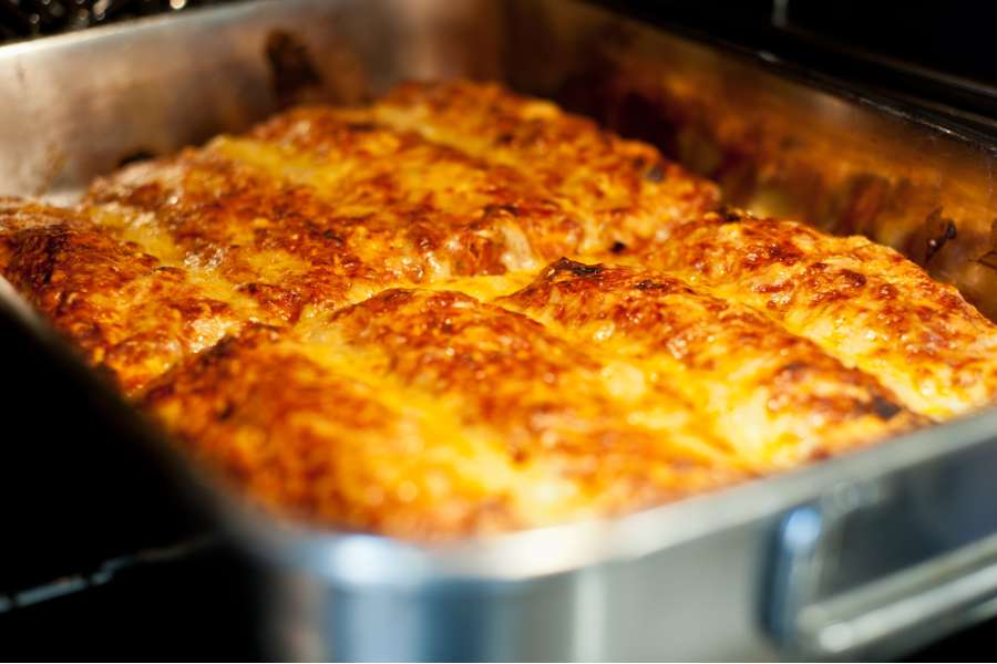 Rezept Foto Mexikansiche Enchillada. Ein Blick in den Ofen, die Enchilladas werden gerade gold gelb gebacken.
