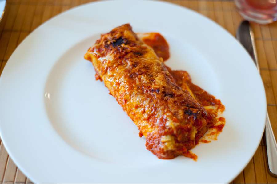 Rezept Foto Mexikansiche Enchillada. Die Enchilladas angerichtet auf einem china bone Teller mit einem Klecks Tomatensauce.