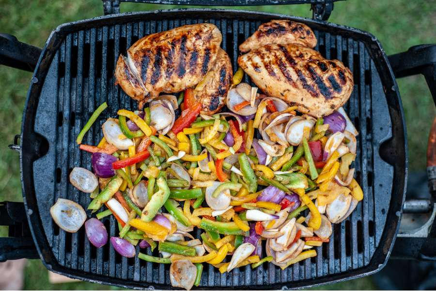 Rezept Foto Mexikansiche Grill Fajitas. Der Gasgrill von oben mit den fertig scharf angegegrillten Hähnchen und dem knackigen Gemüse, dass noch scharf angebraten wird.