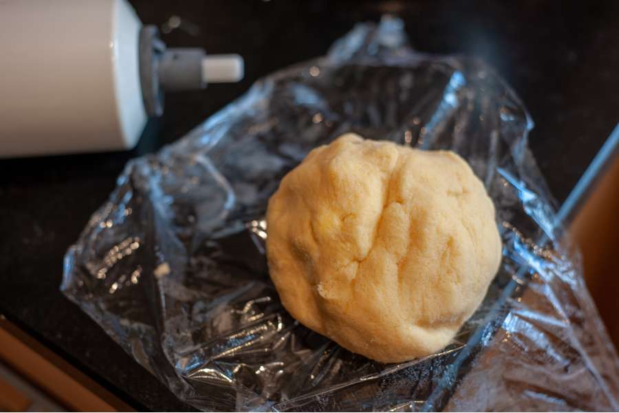 Rezept Foto Ammerthal Nussecken. Der geschmeidige Teig liegt als Kugel auf einer Frischhaltefolie.