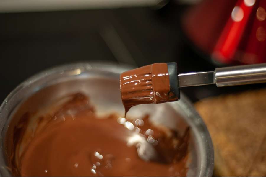 Rezept Foto Ammerthal Nussecken. Der Pinsel wird gerade in die Zartbitterkuvertüre getaucht und gleich auf die Nussecken gestrichen.