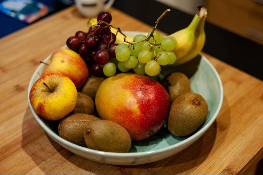 Rezept Foto Grüner Power Früchte Smoothie. Alle Früchte in einer Tonschale angerichtet, daneben ein Schneidebrett.