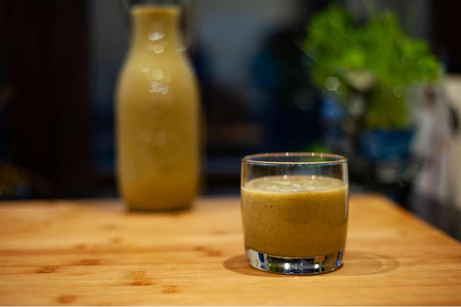 Rezept Foto Grüner Power Früchte Smoothie. Rezeptfoto vom fertig angerichteten Smoothie in einem Tumbler. Im Hintergrund steht ein Weckglas voll mit Smoothie.