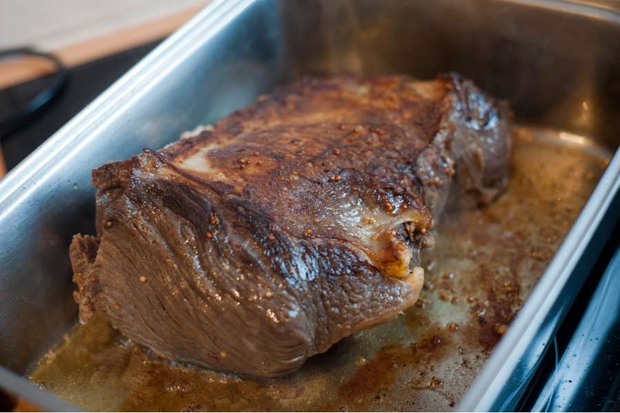 Rezept Foto Sauerbraten mit Serviettenknödel. Seitenansicht des Sauerbratens im Bräter. Die Kruste des Bratens nimmt langsam Form an.