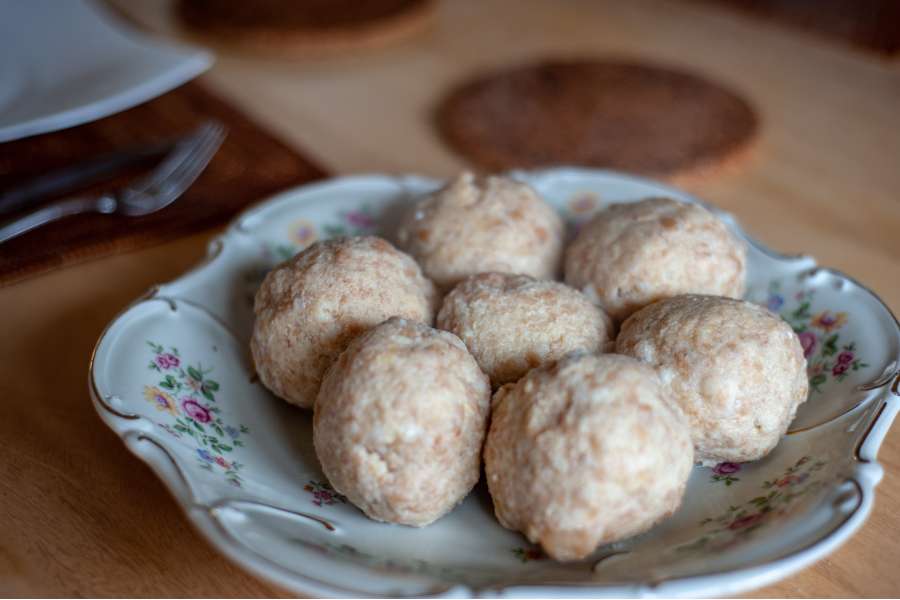 Rezept Foto selber gemachte Semmelknödel. Die gold gelben Semmelknödel liegen in einer alten handbemalten Schüssel und sind für das Servieren bereit. Passt am besten zu rahmigen Braten.